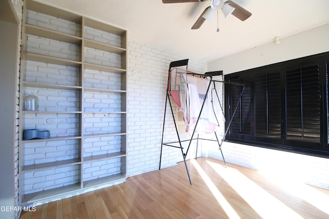 unfurnished bedroom with wood finished floors and brick wall