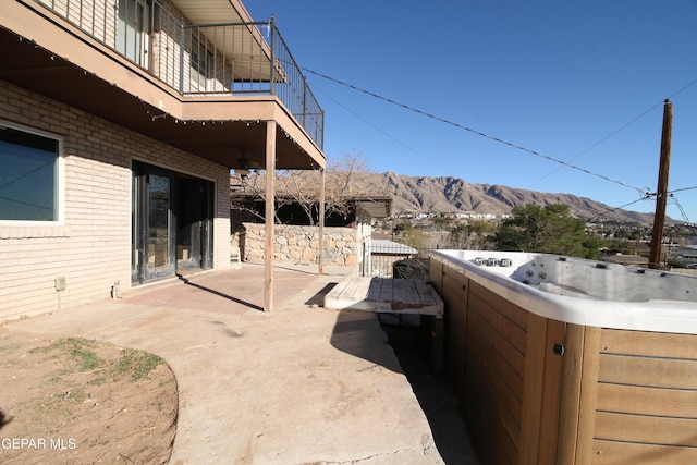 view of patio / terrace with a mountain view, a balcony, and a hot tub