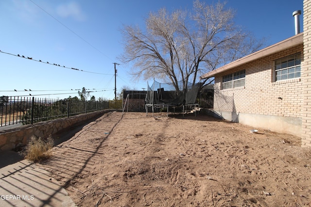 view of yard with a trampoline and fence