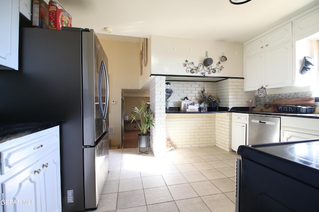 kitchen featuring light tile patterned floors, appliances with stainless steel finishes, white cabinetry, and dark countertops