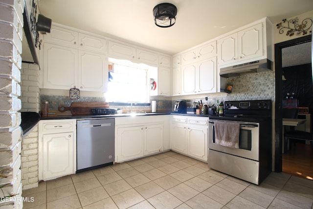 kitchen with dark countertops, backsplash, under cabinet range hood, stainless steel appliances, and white cabinetry