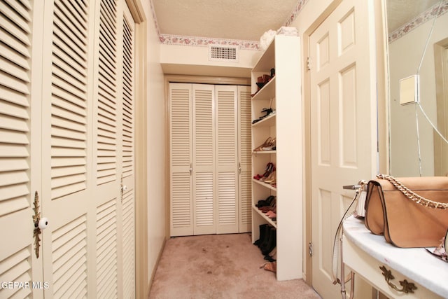 walk in closet with visible vents and light carpet