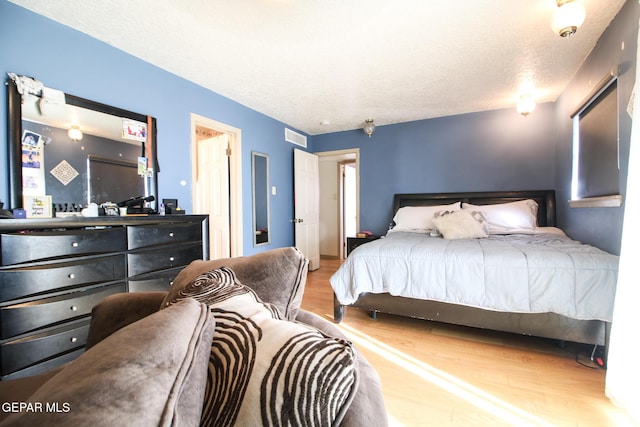 bedroom with wood finished floors, visible vents, and a textured ceiling