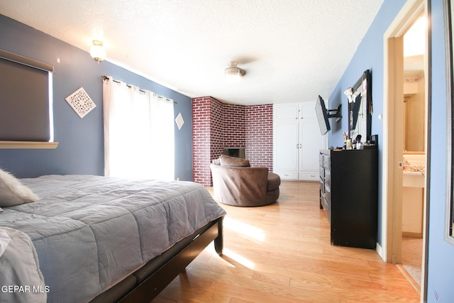 bedroom featuring connected bathroom, a textured ceiling, and wood finished floors