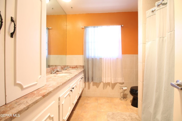 bathroom featuring double vanity, a sink, tile patterned flooring, tile walls, and toilet