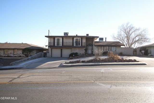 tri-level home with brick siding, an attached garage, a balcony, and driveway