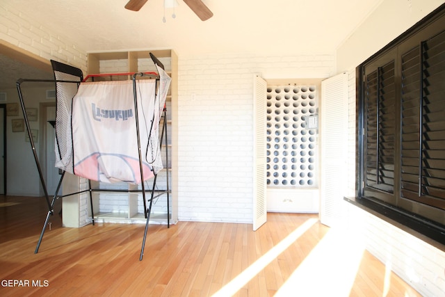 unfurnished bedroom with wood finished floors and brick wall