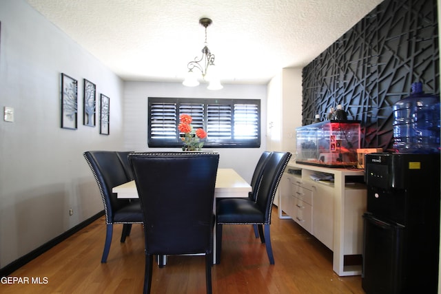 dining space featuring an inviting chandelier, wood finished floors, baseboards, and a textured ceiling