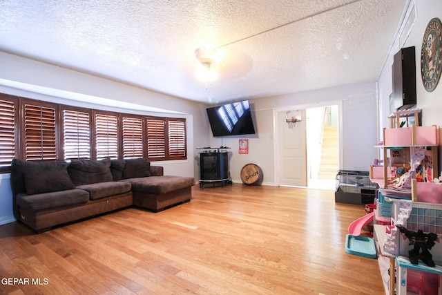 living room featuring baseboards, a textured ceiling, and wood finished floors