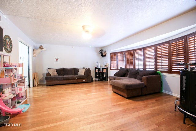 living area featuring baseboards, a textured ceiling, and wood finished floors