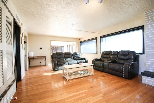 living room with light wood-type flooring and a textured ceiling