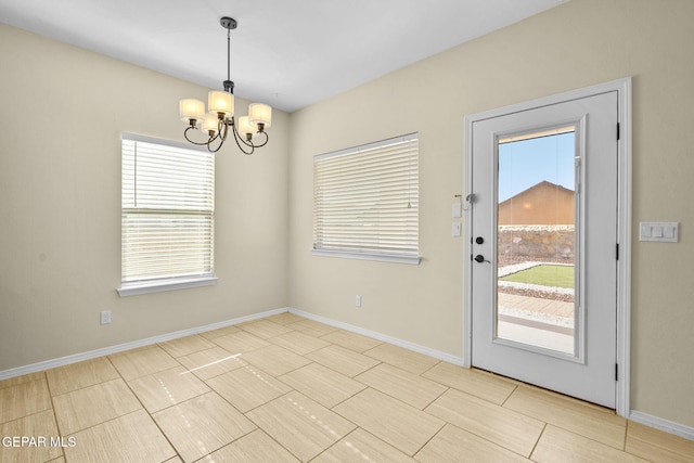 doorway featuring baseboards and a chandelier