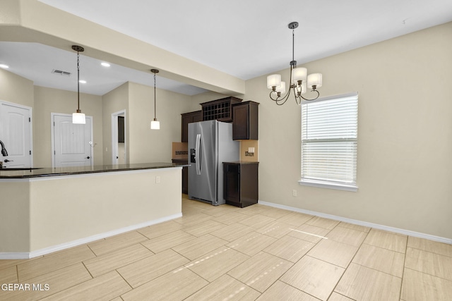 kitchen with dark countertops, visible vents, dark brown cabinets, stainless steel refrigerator with ice dispenser, and a notable chandelier