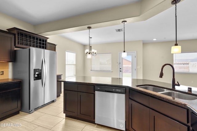 kitchen with a sink, stainless steel appliances, dark brown cabinetry, and a healthy amount of sunlight