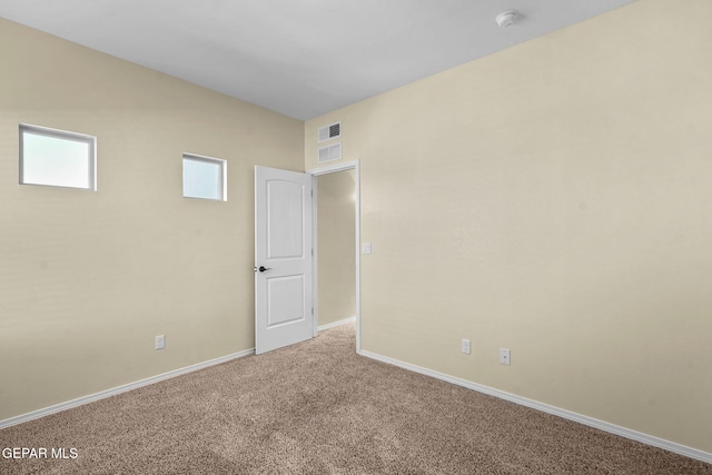 carpeted empty room featuring visible vents and baseboards