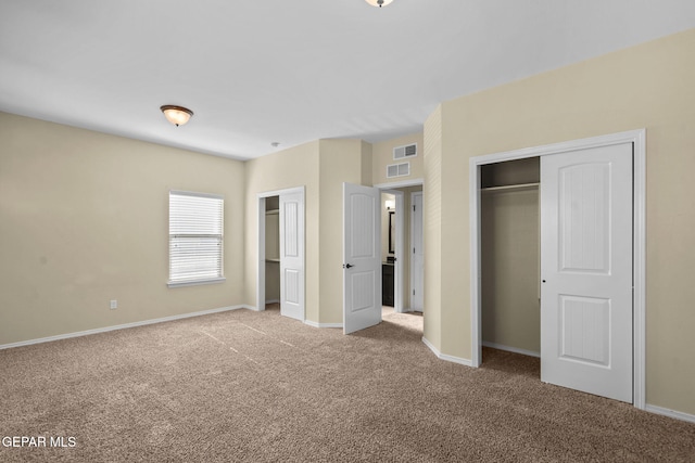 unfurnished bedroom with baseboards, carpet flooring, two closets, and visible vents