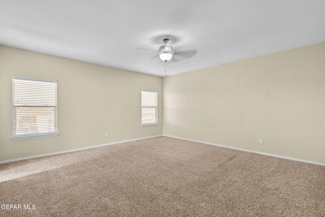 carpeted spare room with a ceiling fan and baseboards