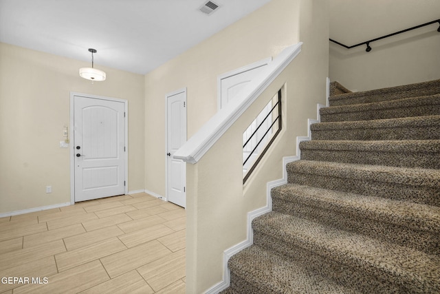 entrance foyer with stairway, baseboards, visible vents, and wood finish floors