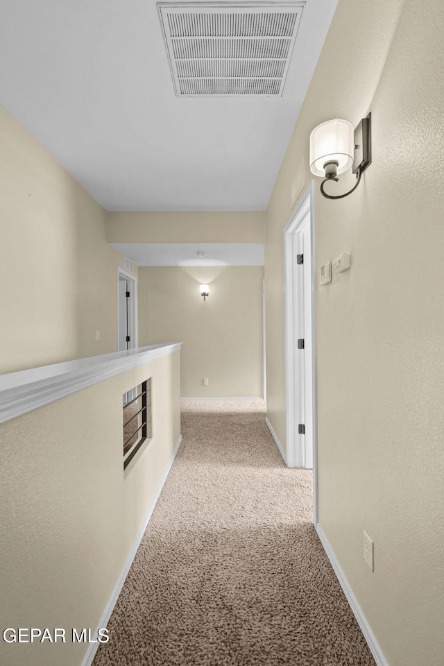 corridor with visible vents, baseboards, and carpet floors