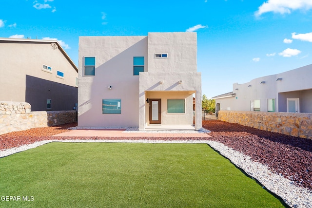 rear view of property featuring stucco siding, a yard, and fence