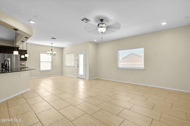 unfurnished living room with visible vents, recessed lighting, ceiling fan with notable chandelier, and baseboards