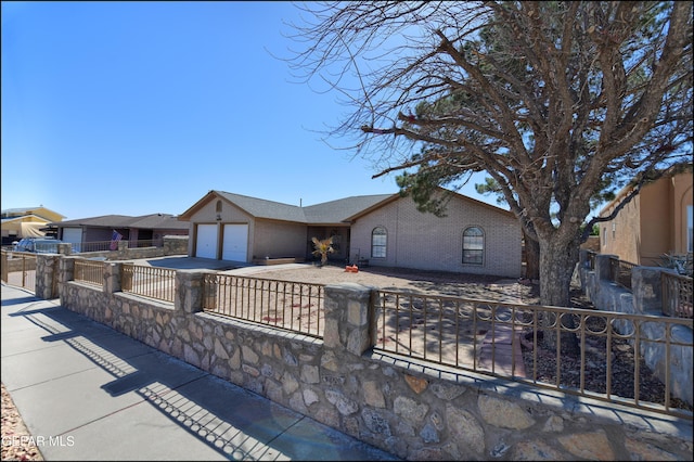 view of front of home with driveway, a garage, brick siding, and a fenced front yard