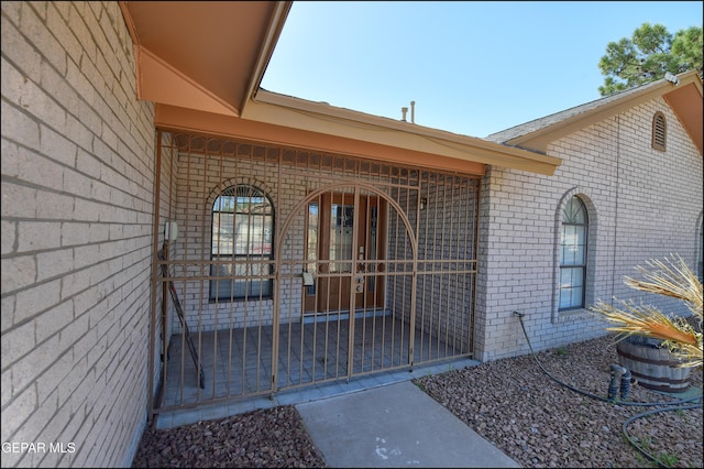 doorway to property featuring brick siding and a porch