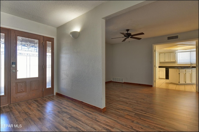 entryway featuring a textured ceiling, a textured wall, visible vents, and light wood-type flooring