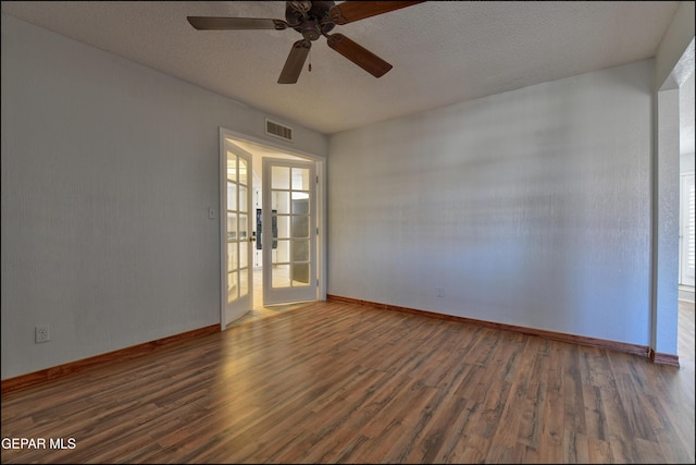 spare room with visible vents, ceiling fan, baseboards, wood finished floors, and a textured ceiling