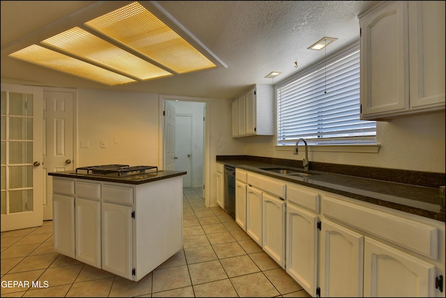 kitchen with dark countertops, a kitchen island, black dishwasher, and a sink