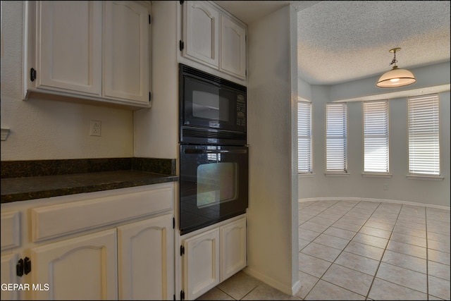 kitchen featuring light tile patterned flooring, black microwave, a textured ceiling, dark countertops, and decorative light fixtures