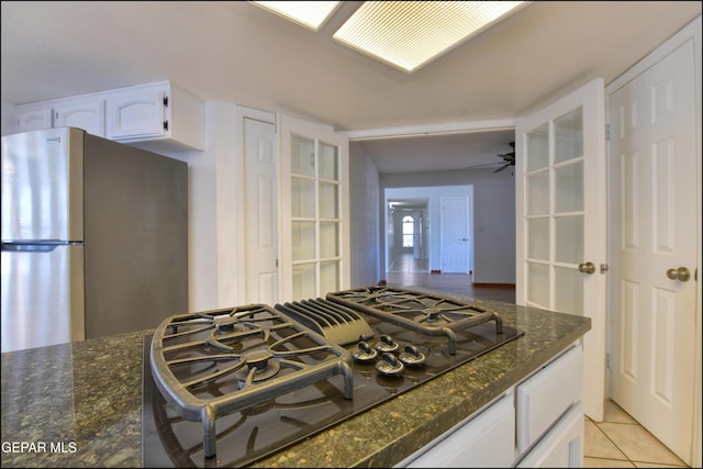 kitchen featuring black gas cooktop, white cabinetry, dark stone countertops, and freestanding refrigerator