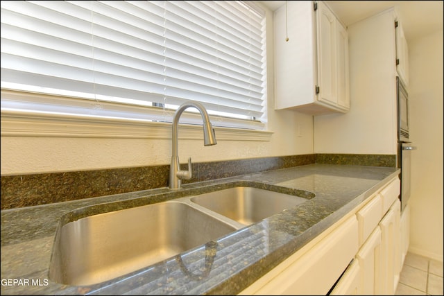 room details featuring dark stone countertops, white cabinets, oven, and a sink