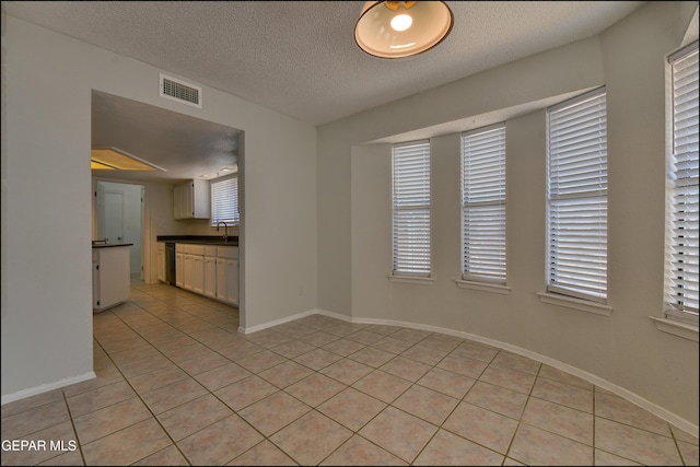 unfurnished room featuring light tile patterned floors, visible vents, baseboards, and a sink