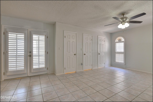 empty room with light tile patterned floors, french doors, a textured ceiling, and ceiling fan