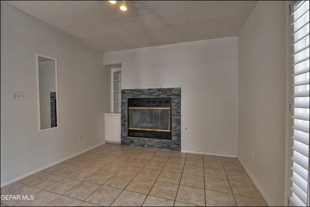 unfurnished living room featuring light tile patterned floors, a glass covered fireplace, a textured ceiling, and baseboards