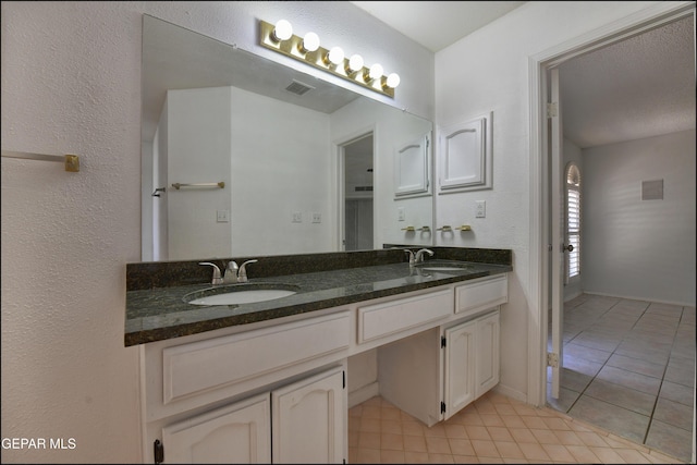 bathroom with double vanity, visible vents, tile patterned floors, and a sink