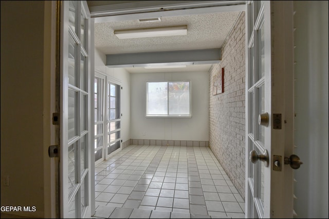 interior space with tile patterned flooring, brick wall, french doors, and a textured ceiling