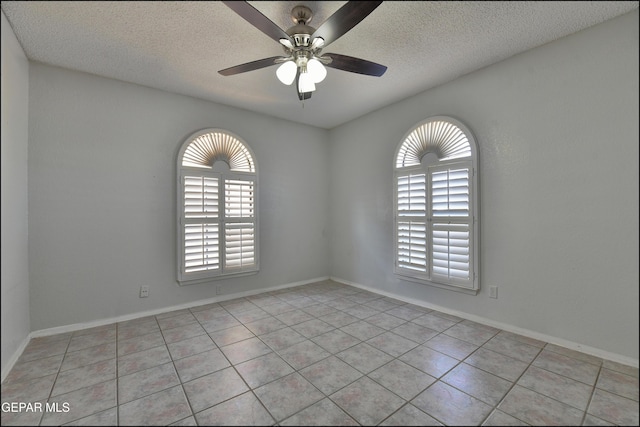 unfurnished room with ceiling fan, light tile patterned floors, baseboards, and a textured ceiling