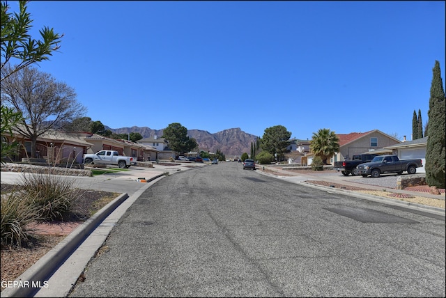 view of street featuring curbs, a mountain view, and a residential view