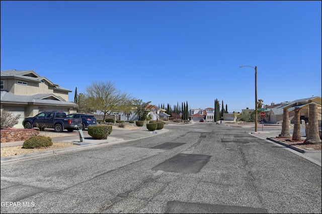 view of road with curbs, traffic signs, a residential view, street lights, and sidewalks