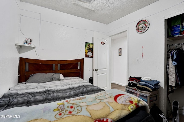 bedroom with a closet, a textured ceiling, and wood finished floors