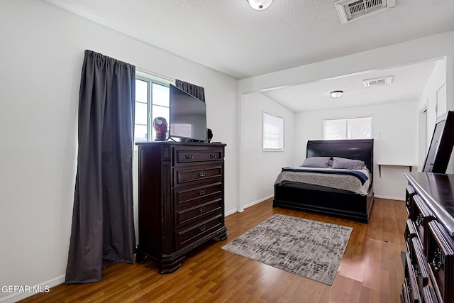 bedroom with visible vents, multiple windows, and wood finished floors