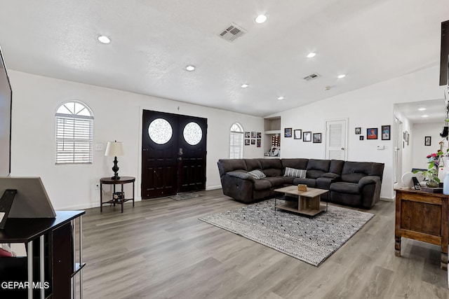 living room featuring recessed lighting, visible vents, light wood-style flooring, and vaulted ceiling