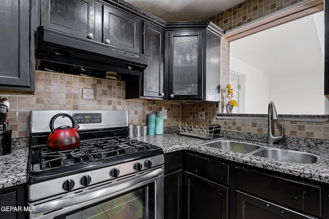 kitchen with stainless steel range with gas cooktop, a sink, decorative backsplash, exhaust hood, and dark cabinets