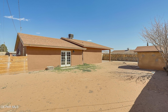 back of house with an outdoor structure, french doors, fence, and stucco siding