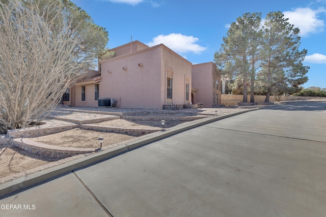 view of side of property with stucco siding and central AC