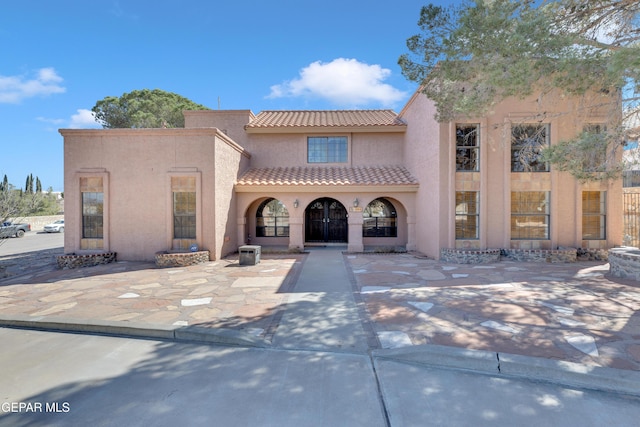 mediterranean / spanish home with a tiled roof and stucco siding