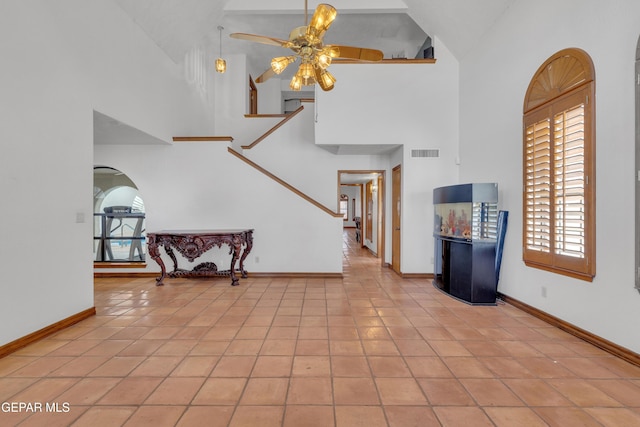 tiled entrance foyer featuring visible vents, baseboards, ceiling fan, arched walkways, and high vaulted ceiling