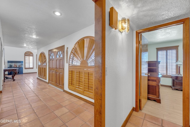 entryway featuring tile patterned floors, plenty of natural light, baseboards, and a textured ceiling